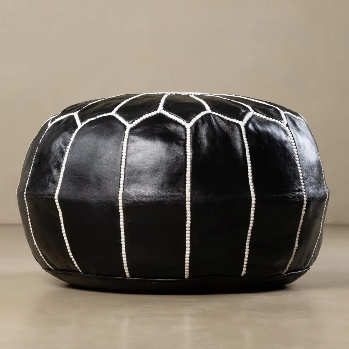 Black leather pouf with white stitching, shown filled